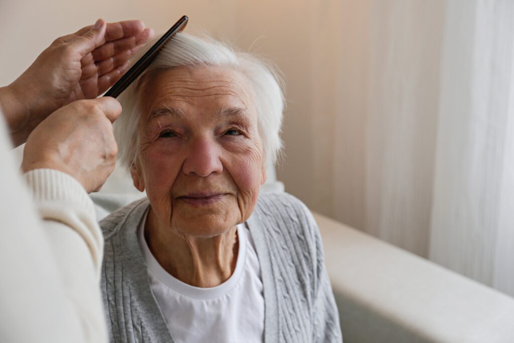 Seniorin erhält Hilfe beim Kämmen – Unterstützung für Senioren mit Problemen auf Mallorca
